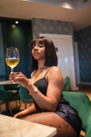 Foto de Foto vertical de una joven experiencia africana degustando vino en un restaurante de lujo - Imagen libre de derechos