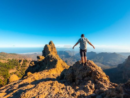 Ein Tourist mit offenen Armen auf dem Gipfel des Pico de las Nieves auf Gran Canaria, Kanarische Inseln