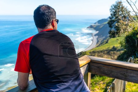 A tourist looking at the beautiful coastal landscape in the flysch of Zumaia, Gipuzkoa. Basque Country