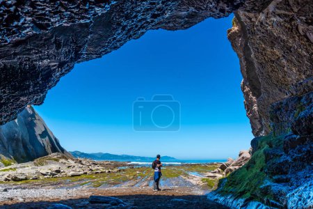 Un randonneur dans la grotte marine de l'anse Algorri sur la côte dans le flysch de Zumaia, Gipuzkoa. Pays basque