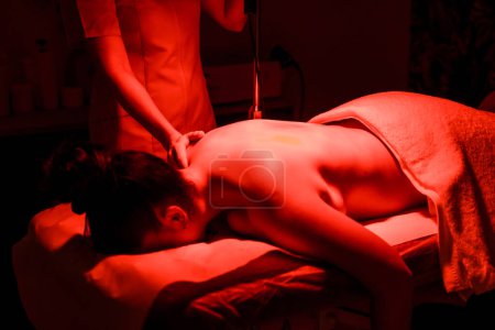 Chiropractic giving a heat massage to a woman lying down in stretcher in the clinic