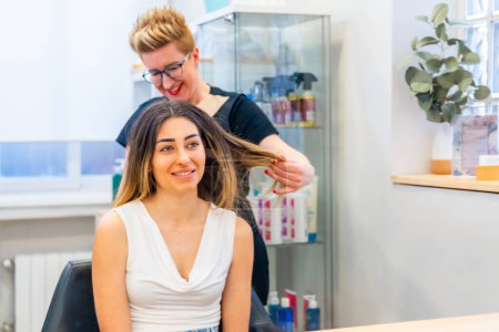Frau im Friseursalon während der Reparatur einer Haarbehandlung im Gespräch mit einem Friseur