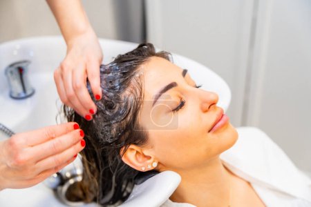 Hairdresser cleaning the hair of a relaxed woman in the beauty salon
