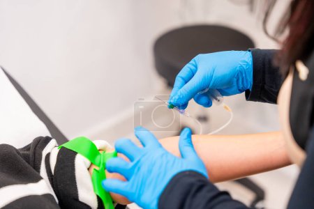 Nahaufnahme einer Expertise mit blauen Latex-Handschuhen zur Entnahme einer Blutprobe einer Patientin in einer modernen Schönheitsklinik