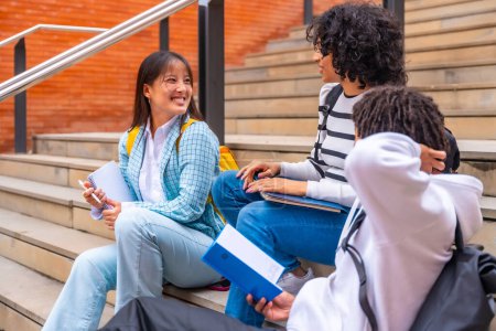 Multi-ethnic students sitting in stairs chatting outside the campus of the university