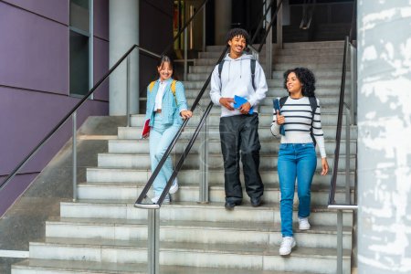 Téléchargez les photos : Les étudiants descendent les escaliers en parlant détendu à l'extérieur du campus universitaire - en image libre de droit