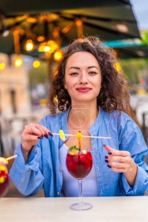 Vertical photo of a woman enjoying a tropical cocktail in an outdoor terrace