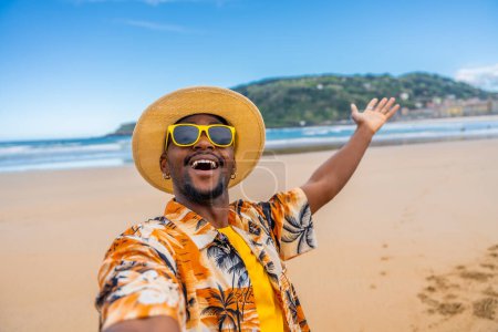Personal point of view of a young african man in colorful clothes, sunglasses and hat taking a selfie enjoying holidays on the beach