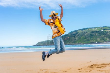 Full length photo of an african american man jumping on the beach