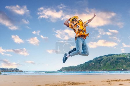 Horizontal full length photo of an african young man jumping celebrating holidays on the beach