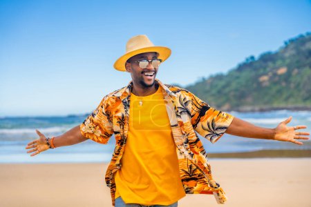 African man in colorful clothes walking with arms opened at beach