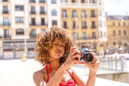 Beauty brunette woman with curly hair taking photos visiting a city in the summer