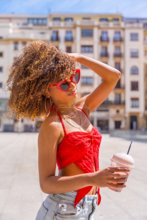 Vertical side view portrait of a sensual woman in summer clothes drinking shake in the city
