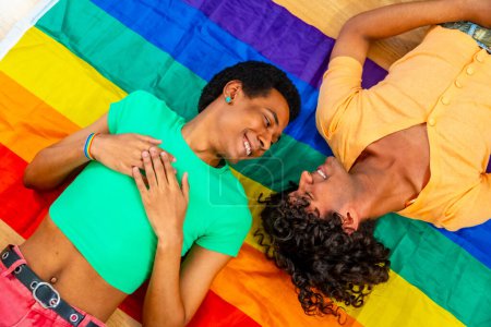 Top view of male latin gay couple lying on rainbow LGBT flag
