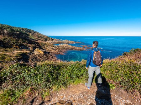 Ein junger Mann blickt auf die wunderschöne Bucht am Berg Jaizkibel in der Nähe von San Sebastian, Gipuzkoa, Baskenland