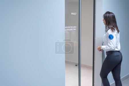 Foto de Beautful gerente del banco femenino abriendo o bloqueando la puerta de la bóveda del banco de seguridad - Imagen libre de derechos