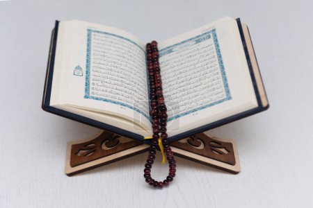 Photo for The words on Qoran is arabic words which means the Holy Qoran. Muslim beads and Koran on wooden table. Islamic concept. - Royalty Free Image