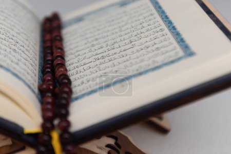 Foto de Las palabras en el Corán son palabras árabes que significan el Sagrado Corán. Cuentas musulmanas y Corán sobre mesa de madera. Concepto islámico. - Imagen libre de derechos