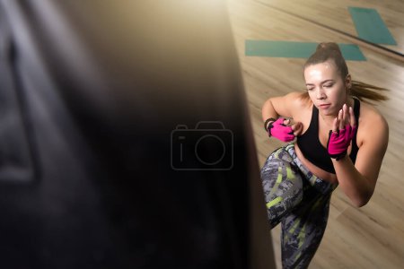 Téléchargez les photos : Jolie entraînement de kickboxer féminin avec un sac de boxe - en image libre de droit