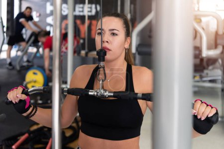 Foto de Young beautiful sporty woman is doing exercises in a fitness room. Gym workout - Imagen libre de derechos