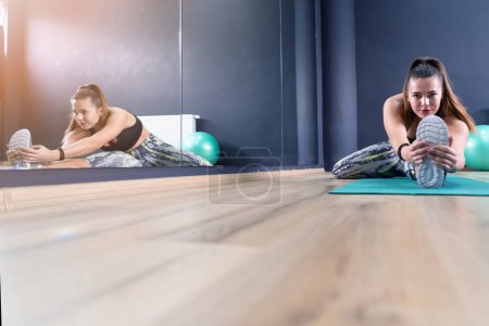 Téléchargez les photos : Young beautiful sporty woman is doing exercises in a fitness room. Gym workout - en image libre de droit