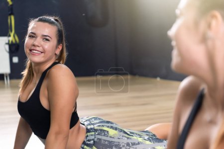 Foto de Young beautiful sporty woman is doing exercises in a fitness room. Gym workout - Imagen libre de derechos