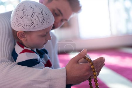 Téléchargez les photos : Famille musulmane priant. Homme et enfant priant. Fin du jeûne. Hari Raya jour. Célébration de l'Aïd al-Fitr - en image libre de droit