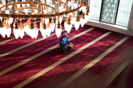 Foto de Hombre árabe musulmán haciendo oración tradicional a Dios y leyendo el Corán mientras usa ropa árabe tradicional durante el ramadán - Imagen libre de derechos