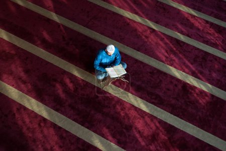 Téléchargez les photos : Arabe Musulman Faire la prière traditionnelle à Dieu et lire le Coran tout en portant des vêtements arabes traditionnels pendant le ramadan - en image libre de droit