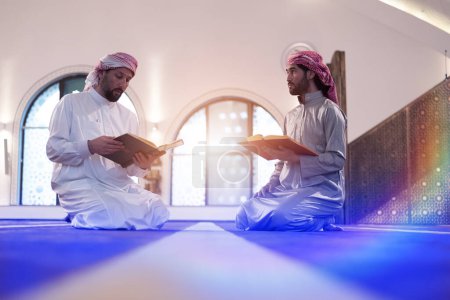 Photo for Read the Qur'an on the day of Ramadan. Two Young Muslim men reading Qur'an together at mosque - Royalty Free Image