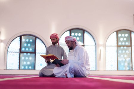Photo for Read the Qur'an on the day of Ramadan. Two Young Muslim men reading Qur'an together at mosque - Royalty Free Image