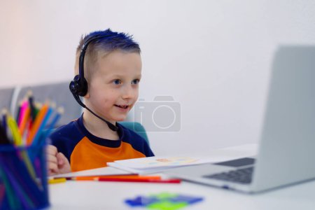 Photo for Adorable child making homework and using notebook and modern gadgets. Home schooling concept. - Royalty Free Image
