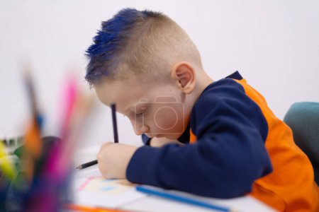 Téléchargez les photos : Adorable enfant faisant ses devoirs et utilisant un ordinateur portable et des gadgets modernes. Concept d'enseignement à domicile. - en image libre de droit