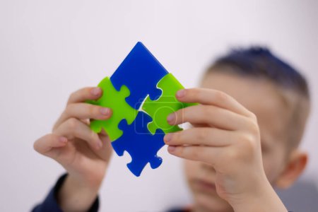 Photo for Kid boy is putting together a big colored puzzle - Royalty Free Image