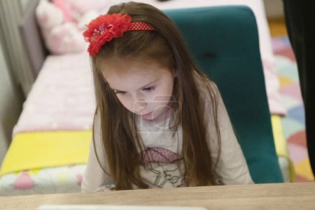 Téléchargez les photos : Petite fille utilisant son ordinateur portable dans sa chambre - en image libre de droit