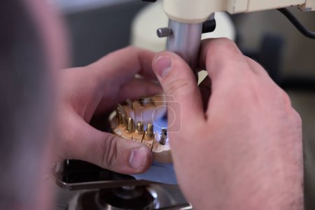 Foto de Técnico dental que trabaja con prótesis dental en laboratorio de prótesis - Imagen libre de derechos