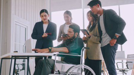 Téléchargez les photos : Un employé handicapé de l'entreprise explique un programme informatique à un groupe de collègues. - en image libre de droit