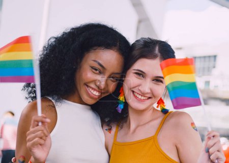 Photo for A lesbian couple with a rainbow tattoo sticker and flag representing the symbol of homosexuality in a pride parade. - Royalty Free Image
