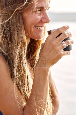 smiling lady drinking tea, looking at side, happy woman on river or lake, portrait. beautiful excited female with long hair, at summer evening. relax, rest, people lifestyle concept
