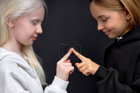 Photo for Two best friends has their own body secret language, children joining their fingers , shows unity , friendship , fun isolated black background - Royalty Free Image