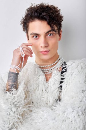 Porträt eines selbstbewussten kaukasischen Männchens, das weiblich aussieht, in weißem, flauschigem Mantel, isoliert auf weißem Studiohintergrund. jugend, schönheit, mode, stil, party, lgbt, transsexuelles konzept