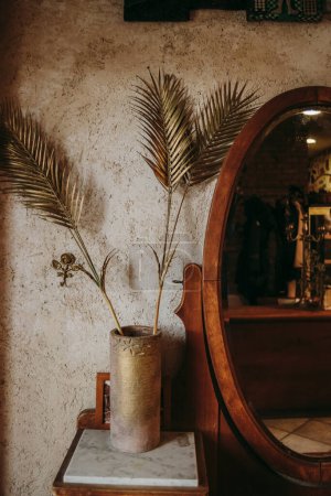 Téléchargez les photos : Intérieur de style antique avec des feuilles dans un vase et miroir - en image libre de droit
