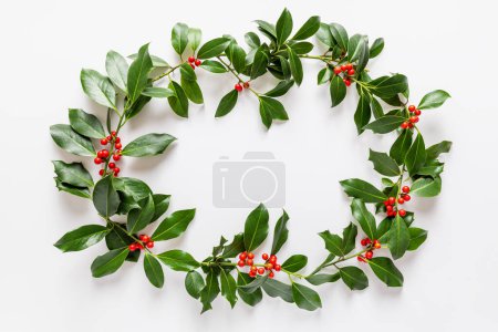 Téléchargez les photos : Cadre de Noël fabriqué à partir de houx frais berries.Winter décoration naturelle. Pose plate festive botanique, vue sur le dessus. - en image libre de droit