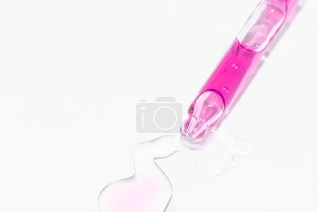 Téléchargez les photos : Macro close up de compte-gouttes pipette avec sérum liquide rose sur fond blanc pour votre projet beauté - en image libre de droit