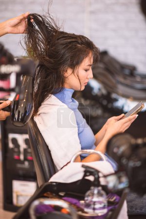 Foto de Peluquería usando secador de pelo para soplar cabello de cliente mujer en salón de belleza. - Imagen libre de derechos
