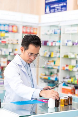 Photo for Pharmacist man using digital tablet for check medicine inventory in drug store, Medical service online, Telemedicine to giving medical information to online customer and patient. - Royalty Free Image