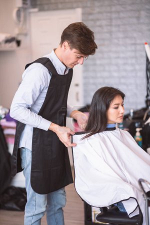 Foto de Peluquero profesional hombre que se prepara para hacer un nuevo estilo de pelo para la mujer hermosa en el salón. - Imagen libre de derechos