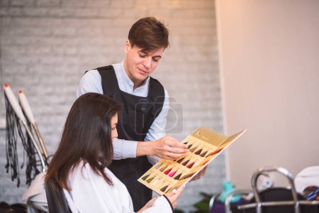 Photo for Hairdresser man giving advice to beautiful woman customer choosing new hair color from pallet in salon. - Royalty Free Image