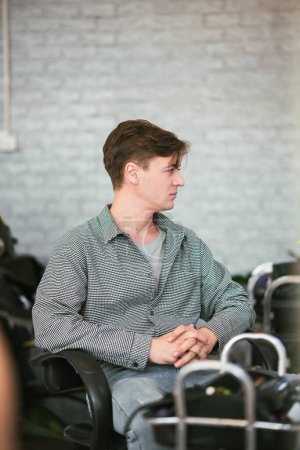 Foto de Hombre caucásico guapo sentado en peluquería aft.er corte de pelo con peluquería profesional. - Imagen libre de derechos