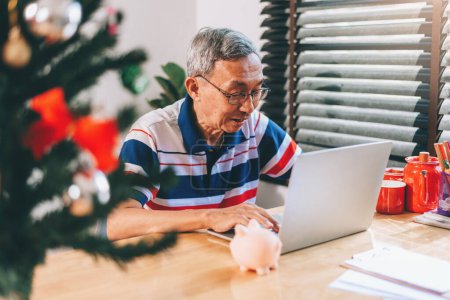 Téléchargez les photos : Asiatique retraité homme utilisant ordinateur portable à la maison salon pour le travail et conférence réunion avec des amis dans la situation covid 19. - en image libre de droit